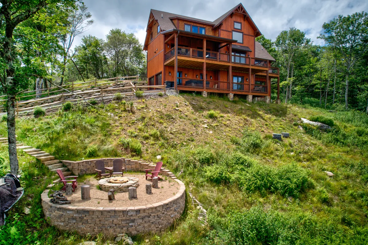 An outdoor fire pit surrounded by comfortable seating, nestled in natural surroundings beside the house. The area is set for cozy gatherings under the stars, with opportunities for storytelling and stargazing evident in the arrangement.